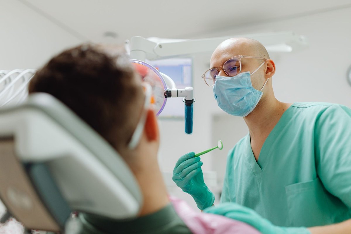 Dentiste examinant une cavité buccale avec une lampe dans une clinique Dentiste examinant une cavité buccale avec une lampe dans une clinique